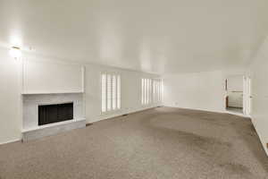 Unfurnished living room with carpet flooring and a fireplace