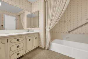 Full bathroom featuring vanity, a bathtub, wallpapered walls, and light colored carpet