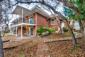 Back of property with stairs, brick siding, a patio area, and a balcony