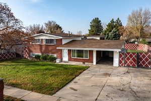 Tri-level home with brick siding, concrete driveway, a chimney, a gate, and roof with shingles