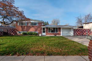 Split level home featuring brick siding, concrete driveway, and an attached garage