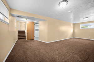 Below grade area featuring stairs, carpet flooring, and a textured ceiling