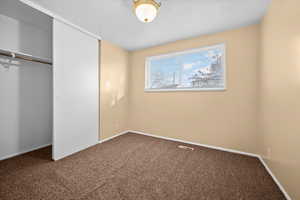 Unfurnished bedroom with carpet flooring and a closet