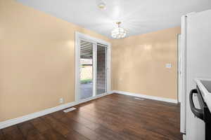Unfurnished dining area with dark wood-type flooring and a chandelier
