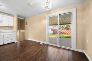 Unfurnished dining area featuring dark wood-style flooring and a chandelier