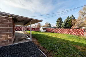 Fenced backyard featuring a patio area and a storage shed