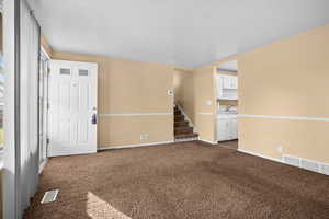 Unfurnished room featuring dark colored carpet and stairs