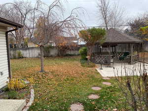 Fenced backyard featuring a patio and a gazebo