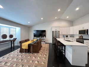 Living area open to kitchen with vaulted ceilings and a lot of natural light