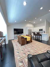 Living area featuring dark wood flooring, vaulted ceiling, and recessed lighting