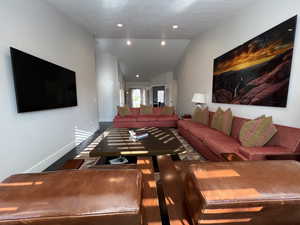 Living room featuring vaulted ceiling, wood flooring and recessed lighting