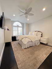 Guest bedroom with a ceiling fan, dark wood finished floors.