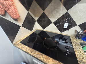 Kitchen view of black electric stovetop and light stone counters