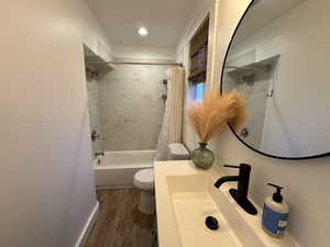 Full bath featuring vanity, shower / bath combo, and dark wood-style flooring