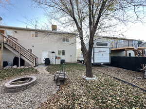 Back of house featuring stairway, an outdoor fire pit, a chimney, and a deck