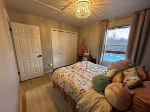 Bedroom with light wood-style floors, a closet, and a textured ceiling