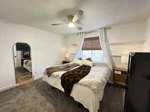 Bedroom with a textured ceiling, dark carpet, and ceiling fan
