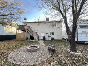 Back of property featuring an outdoor fire pit, stairway, and a deck