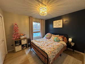 Bedroom featuring light wood-style flooring, a textured ceiling, and a closet