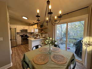 Dining space with a chandelier, dark wood-style floors, and vaulted ceiling