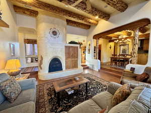 Tiled living area featuring a fireplace, beamed ceiling, and a chandelier