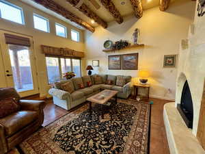 Tiled living room featuring a high end fireplace, a towering ceiling, and beam ceiling
