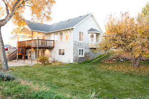 Rear view of house with a patio area, a yard, stairs, and stone siding