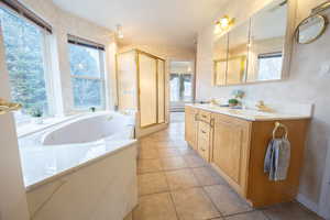 Bathroom with a jetted tub, double vanity, light tile patterned floors, a stall shower, and plenty of natural light