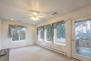 Empty room featuring baseboard heating, carpet floors, and ceiling fan