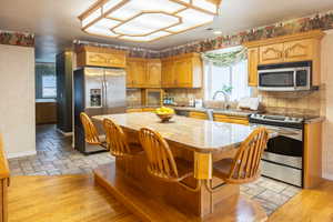 Kitchen with stainless steel appliances, a center island, light stone countertops, healthy amount of natural light, and wallpapered walls
