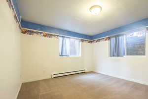 Unfurnished room with baseboard heating and light colored carpet