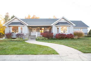 Ranch-style house featuring a front lawn, a shingled roof, and a porch