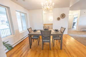 Dining space with light wood-type flooring, baseboard heating, a chandelier, and a baseboard heating unit