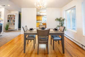 Dining space with baseboard heating, light wood-style floors, a chandelier, and recessed lighting