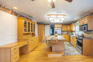 Kitchen featuring appliances with stainless steel finishes, glass insert cabinets, a kitchen island, tasteful backsplash, and recessed lighting