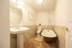 Bathroom featuring a freestanding tub, a wainscoted wall, and tile walls