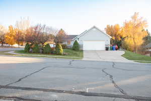 View of front of house featuring driveway, stucco siding, an attached garage, a front lawn, and stone siding