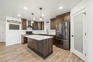 Modern kitchen featuring a generous island, double pendant lighting, stainless steel appliances, and a walk-in pantry with frosted door.
