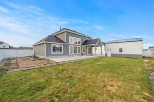 Fully fenced backyard with a large grassy area, concrete patio, and additional outbuilding for storage or hobbies.