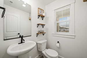 Crisp and modern half bath featuring a pedestal sink, upgraded black fixtures, and natural light from the window.