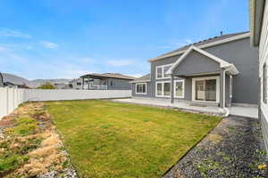 Side angle of the backyard showing open lawn space, rock borders, and the extended patio area.