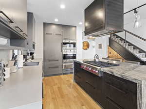 Kitchen featuring decorative backsplash, stainless steel appliances, gray cabinets, light wood-type flooring, and modern cabinets