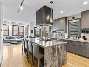 Kitchen with a kitchen bar, rail lighting, gray cabinetry, pendant lighting, and a center island