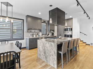 Kitchen with gray cabinets, track lighting, a kitchen breakfast bar, pendant lighting, and a center island