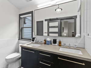 Full bathroom featuring tile walls and double vanity