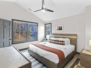 Carpeted bedroom featuring lofted ceiling and a ceiling fan