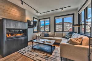 Living area featuring track lighting, a glass covered fireplace, and wood finished floors