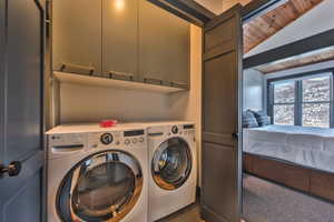 Washroom with lofted ceiling, wooden ceiling, washing machine and clothes dryer, and cabinet space