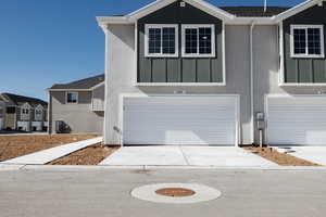 View of front of home with board and batten siding, an attached garage, and concrete driveway