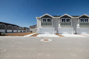 View of front of home with an attached garage, concrete driveway, and a residential view